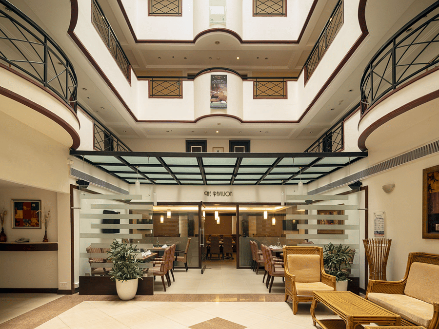 Pavilion at The Residency Karur features a patterned floor, seating areas, and glass-enclosed spaces under a skylight.