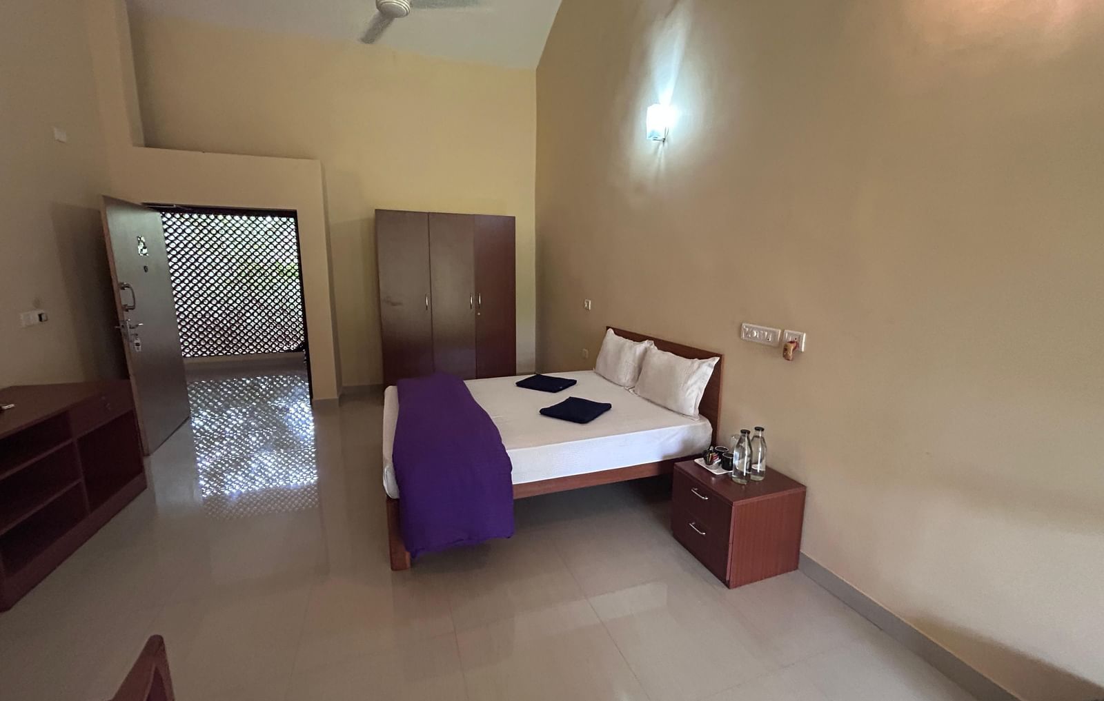 A comfortable room with a large bed, wooden furniture, and a balcony at Paradise Wild Hills Resort, Kollur.