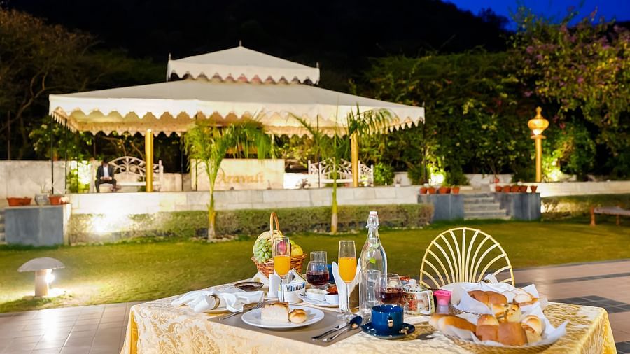 A table with many items on it in the foreground and a canopy in the background - Rajasthali Resort & Spa, Jaipur.