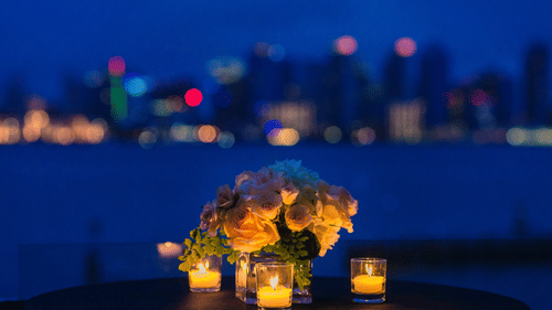 candlelights kept on a table next to a vase with a skyline in the background
