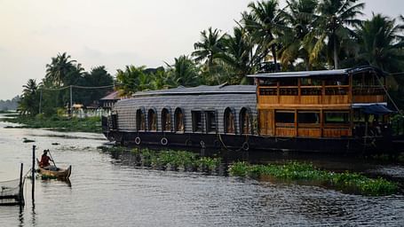 A tranquil houseboat on the backwaters surrounded by lush greenery.