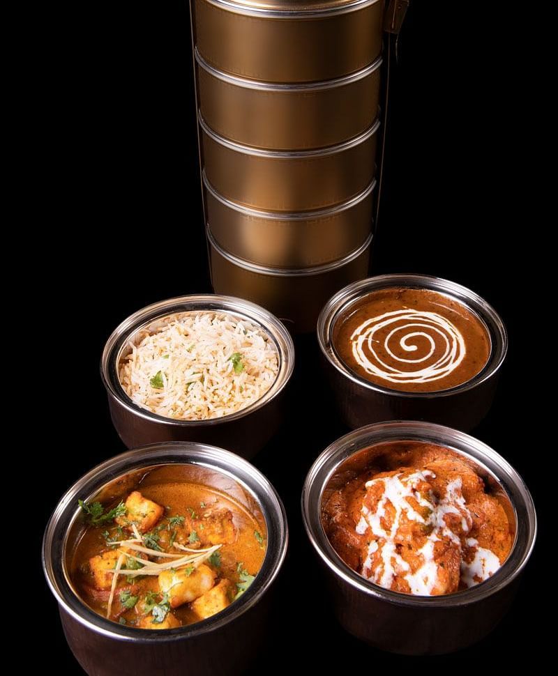image of a tiffin served at  The Claridges New Delhi with delicious food items