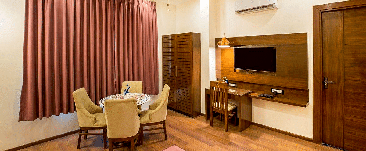 The living area at the Suite with a dining table, a wardrobe, and a wall mounted television at Regenta Inn DLS.