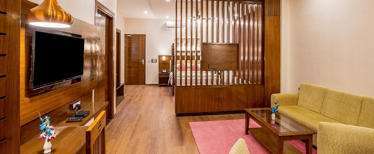 Full view shot of the Suite at Regenta Inn DLS featuring a separate living area along with a wooden partition in the middle separating it from the bedroom.