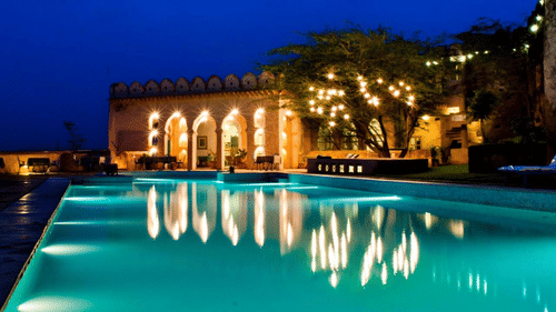 A vibrant blue pool with the resort at the background - Hill Fort Kesroli Alwar Rajasthan