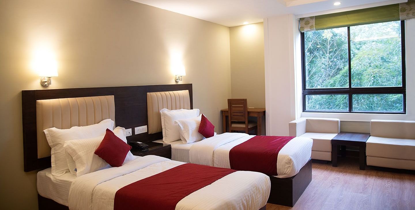 A hotel room in Gangtok featuring twin beds, warm lighting, and a window offering stunning views - Summit North Star, Gangtok