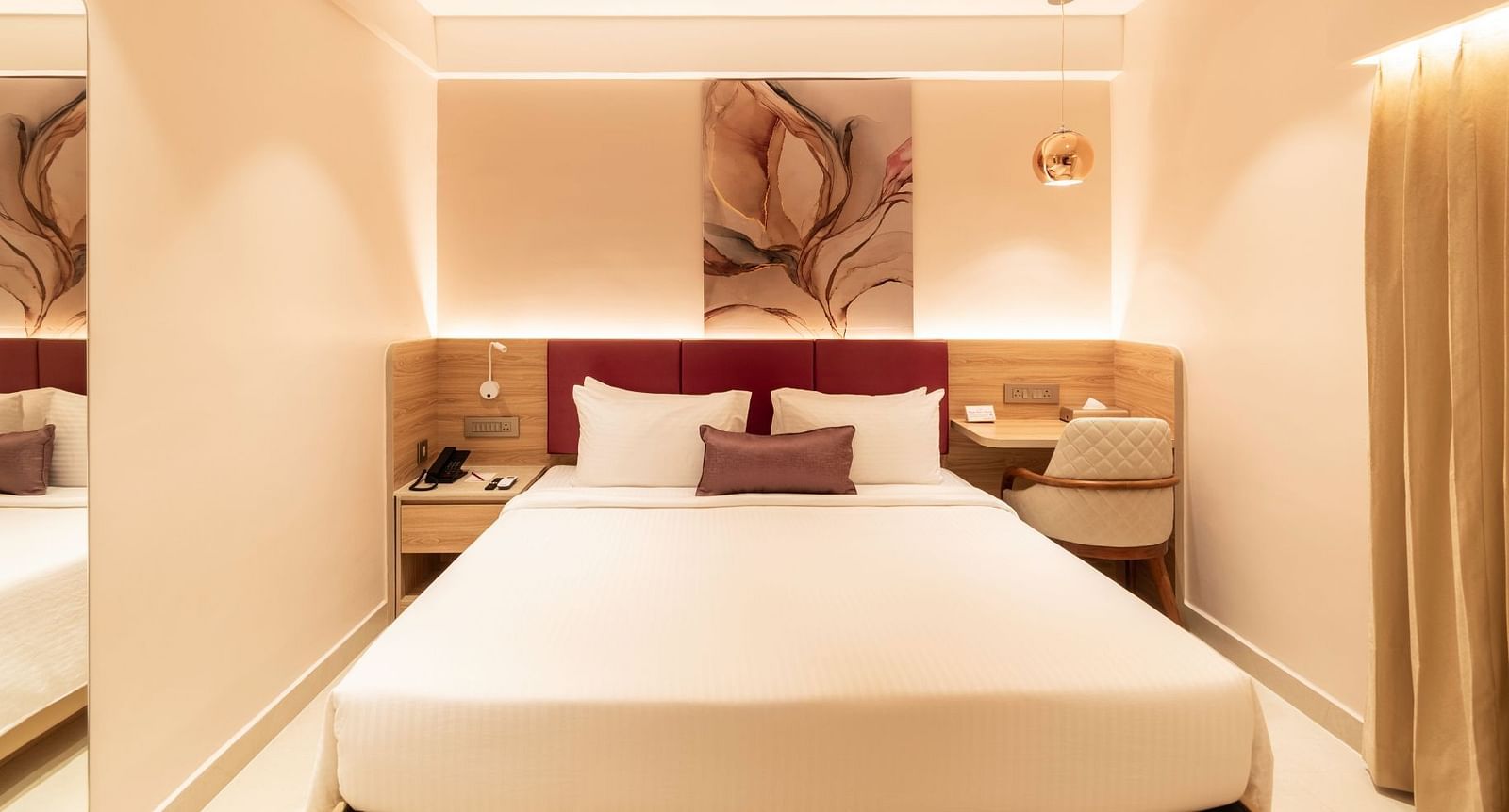 King-sized bed with wall art in The Executive Rooms at Livancia The Sojourn, Bangalore.