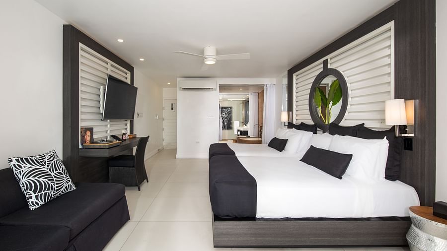 A peak into our room in Montego Bay with a bed placed in front of a wall mounted television and a couch with pillows for relaxation - S Hotel Montego Bay, Jamaica