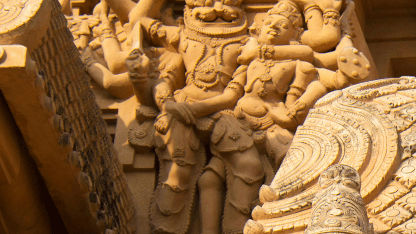 A view of Brihadeeswarar Temple's gopuram having a carving of deity having numerous hands holding another person in a headlock.