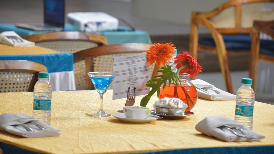 Close up shot of a table with well arranged napkins, cutlery, water bottles, and decorations - Lords Eco Inn Belagavi