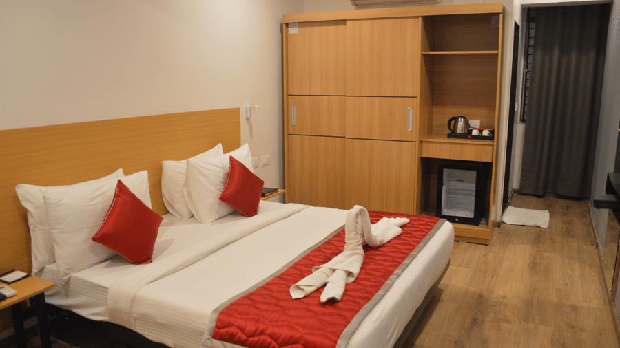Bedroom with a double bed, wooden wardrobe, and red accents - Lords Eco Inn Belagavi