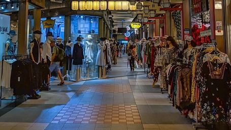 a crown walking inside a mall with clothes hanging outside from the shops inside a mall in Bangkok