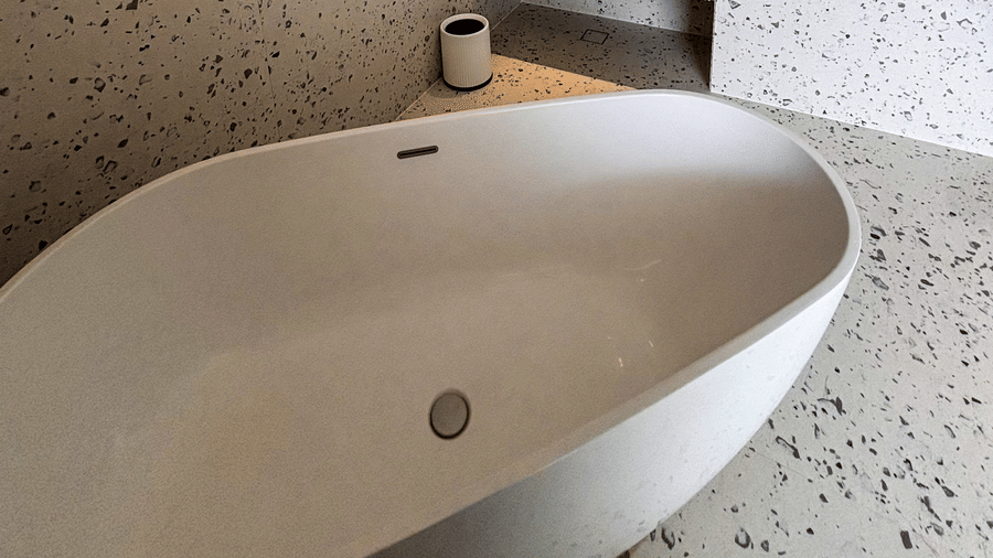 A white freestanding tub and a washbasin area with speckled terrazzo surfaces at Avanya Resorts N Retreat.