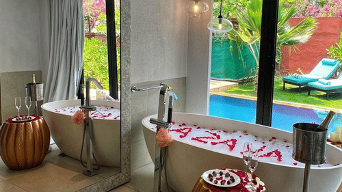 Bathtub filled with a bubble bath and azaya written with rose petals inside the tub - Azaya Beach Resort