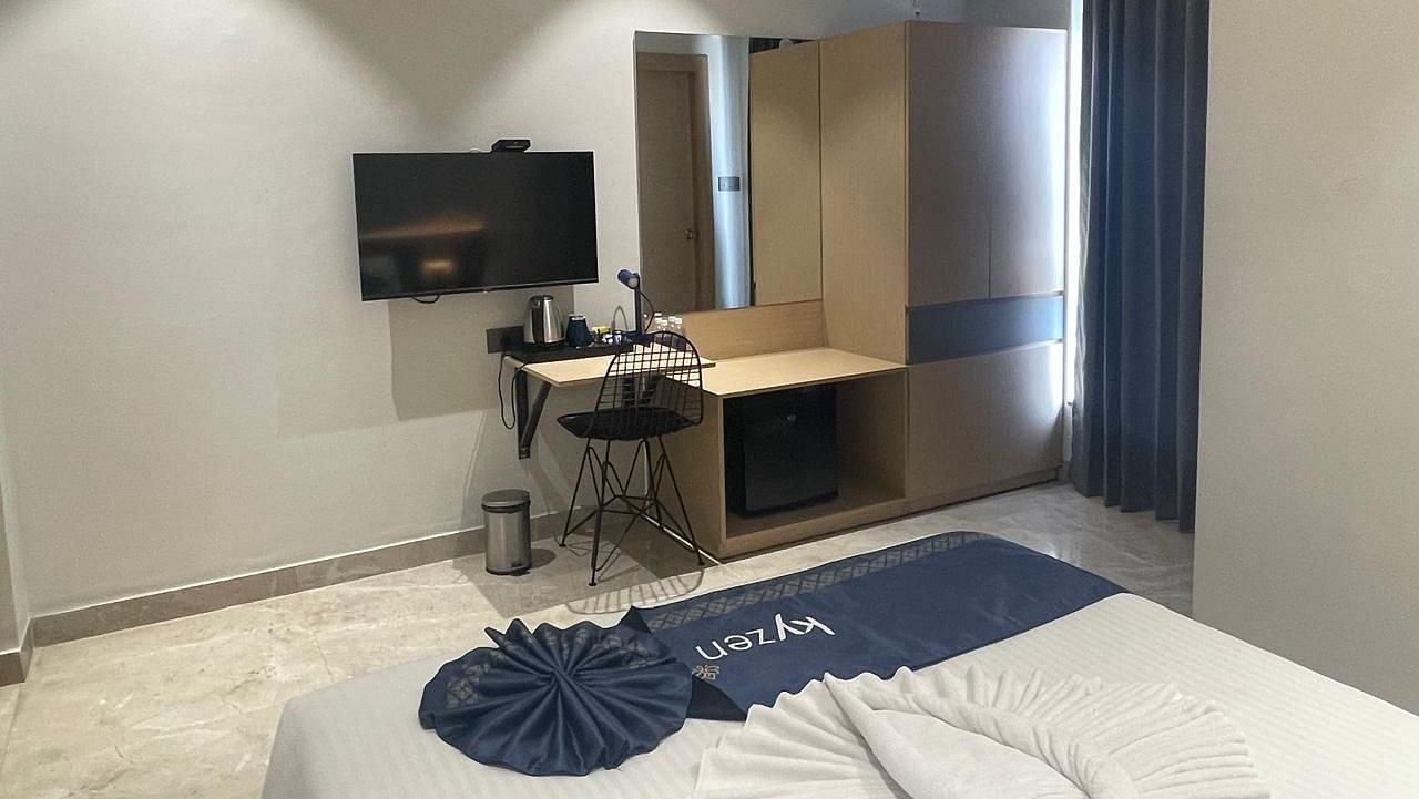 Contemporary suite with a wall-mounted TV, desk, and ample natural light at Hotel Kyzen HiTech City – Your Zenly Stay