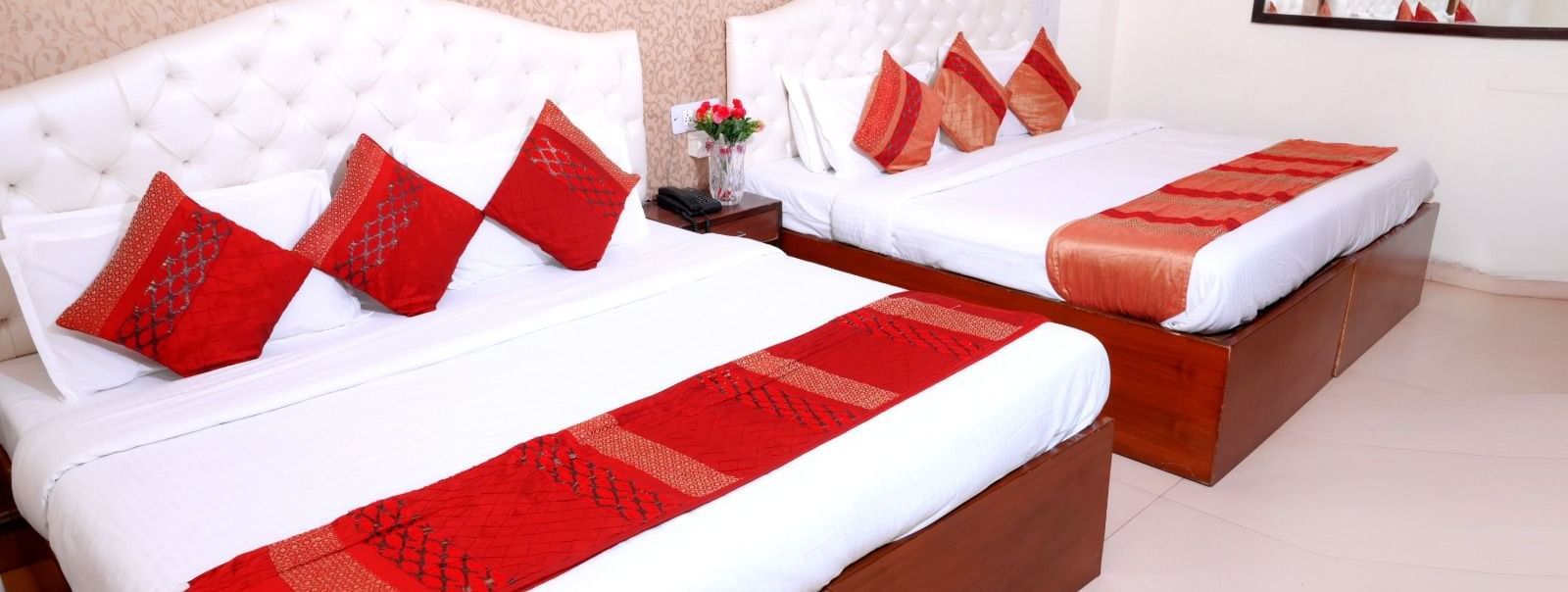 Spacious family room at Hotel Diamond Inn, Chandigarh, with two double beds and coordinated red decor.