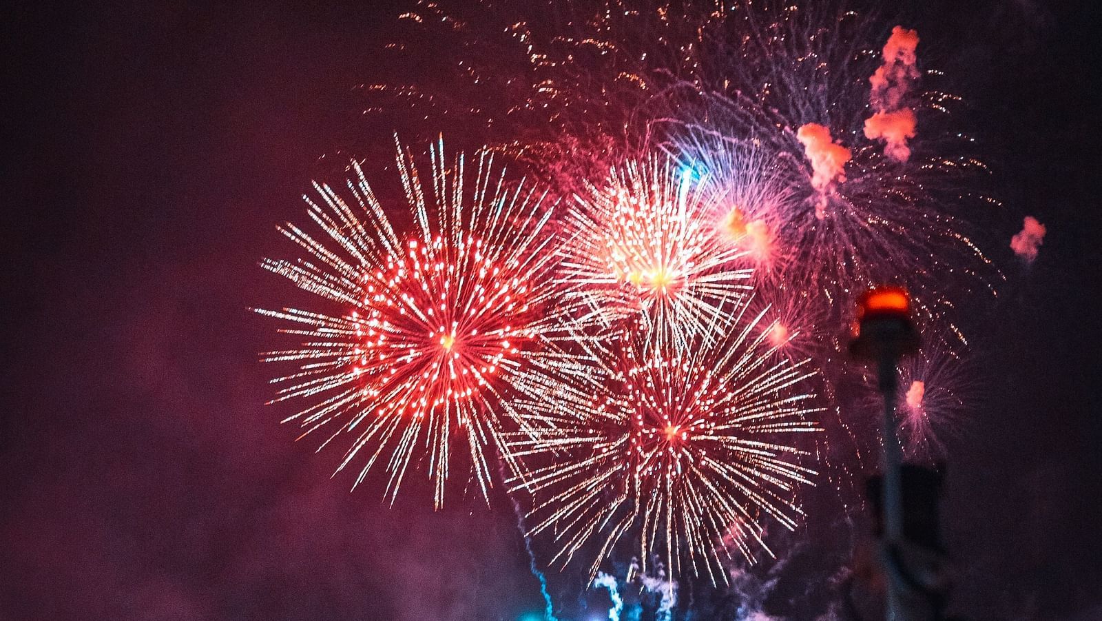 An overview of a lakeside venue with firecrackers in the sky that is illuminated on the waterbody.