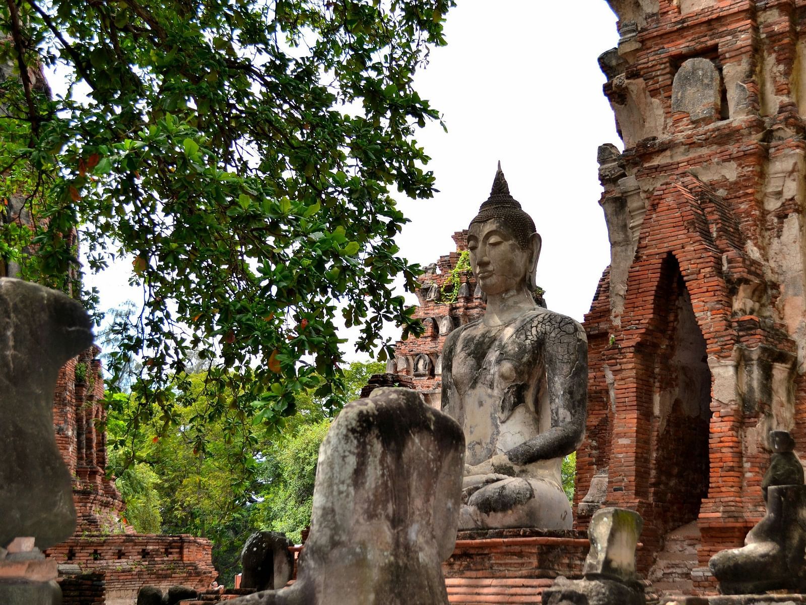 A statue of buddha next to an old building in Ayutthaya Historical Park