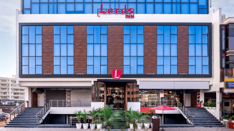 Front view of a modern Lords hotel building with a drop-off area, signage, and a clean facade.