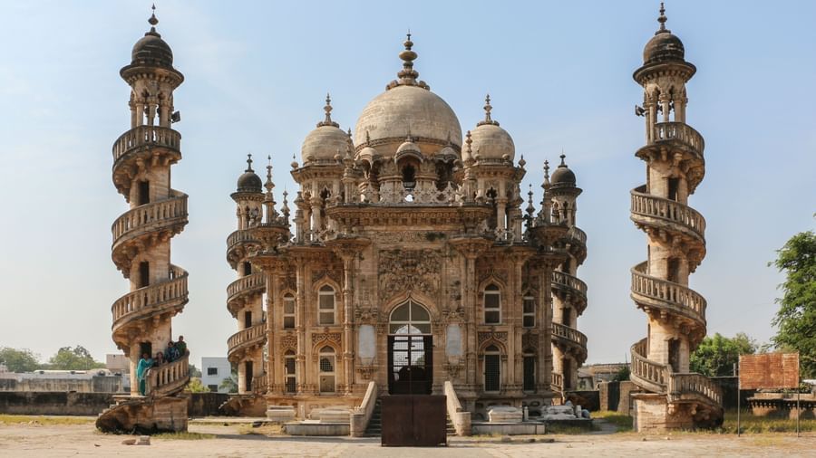 A view of majestic Indo-Islamic mausoleum Mahabat Maqbara with intricate domes and four striking spiral minarets, set against a clear blue sky in Junagadh.