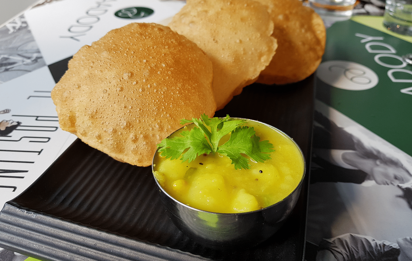 A plate with three pooris and saagu kept on a table