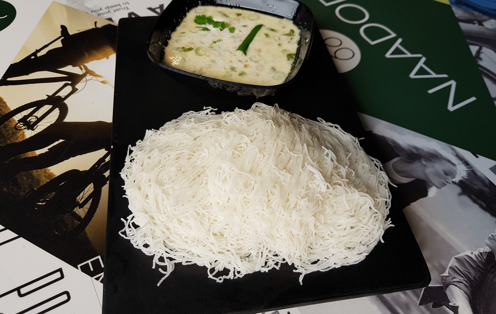 Appam and stew on a black plate kept on a table