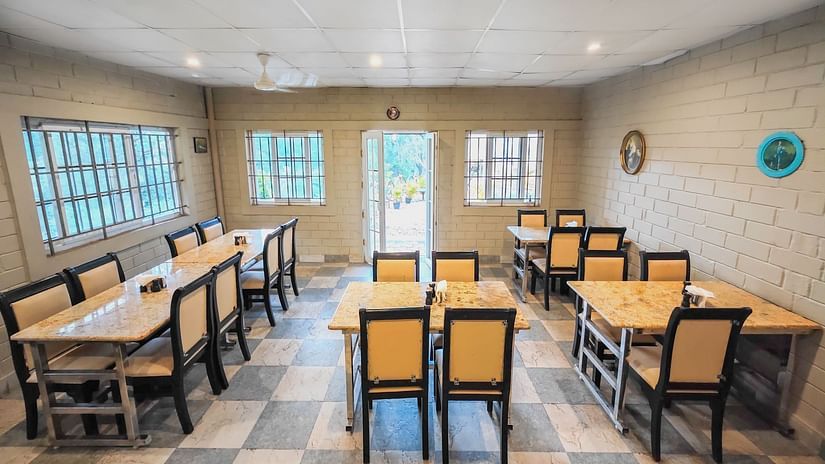 an overview of Seating arrangements inside a restaurant with a brown golden tables and chairs - Ibex Stays & Trails, Valparai (Mistly).