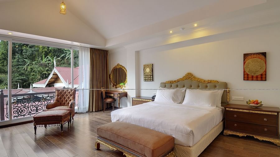 a king size bed and a sofa by the window - Mayfair Spa Resort & Casino Gangtok