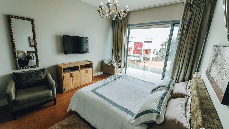 Bedroom with a double bed, television, seating area, and large windows.