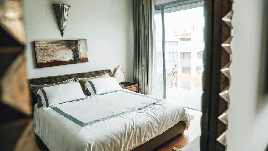 Bedroom with a double bed, television, desk, and curtains.