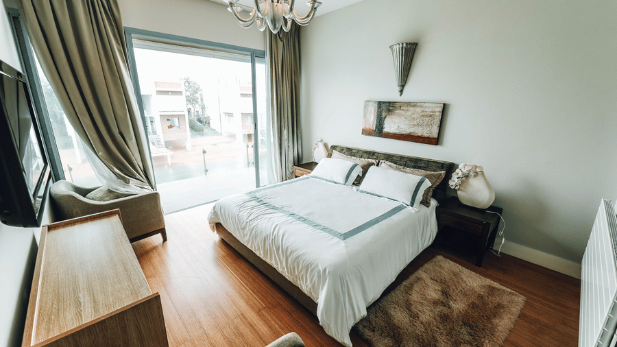 Bedroom with a double bed, desk, chair, television, and large window.