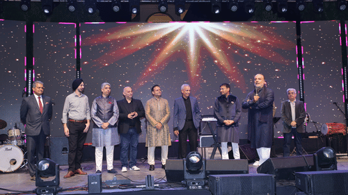 Distinguished guests and speakers on stage during an award ceremony under dramatic lighting.