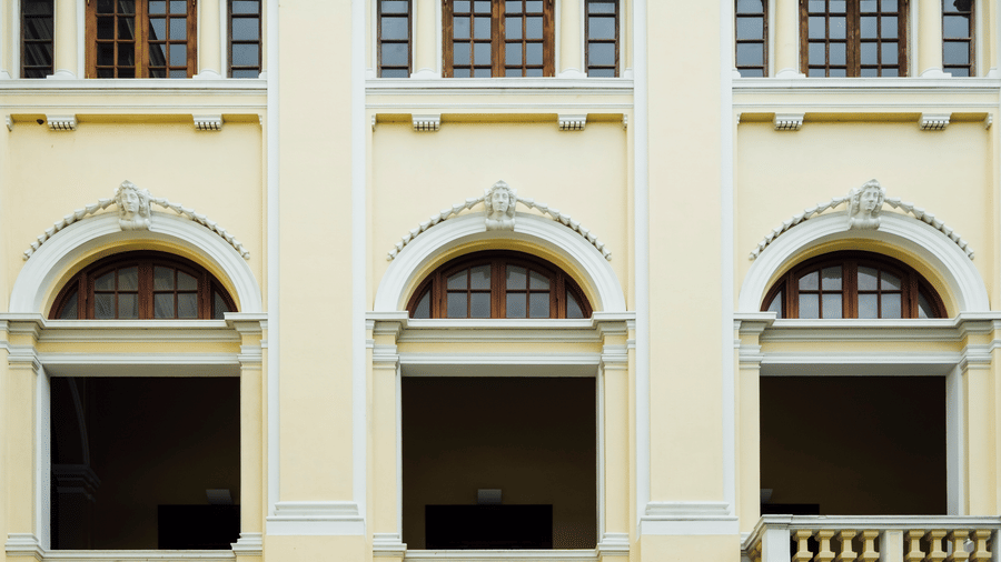 Symmetrical facade of a vintage building with arched windows and decorative columns.