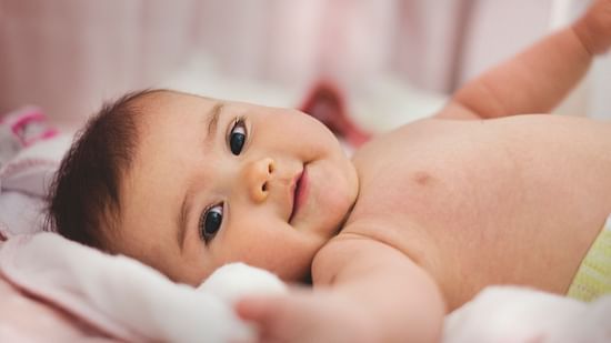Image of an infant looking into the camera while lying in the crib