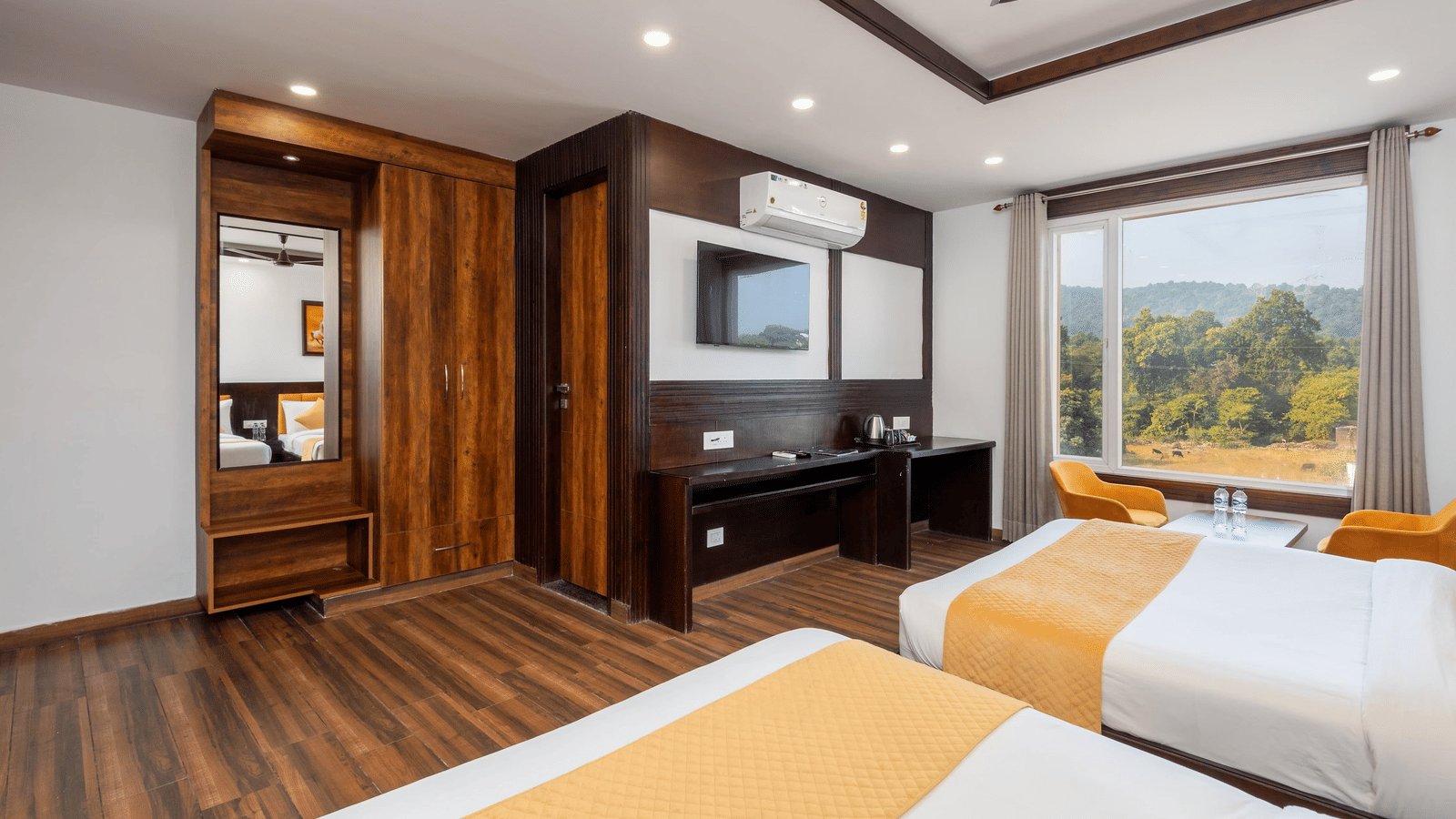 Interior of a room showing beds, a television, wardrobe area, and large window with outside view at Perfectstayz Premium Shanti Heritage, Haridwar.