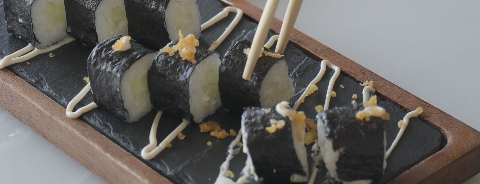 Close-up of a hand placing hors d’oeuvres on a wooden serving tray - Mayfair Cafe & Suites, Dalhousie