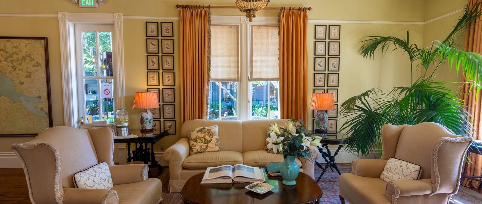A welcoming hotel lounge with comfortable armchairs, a cozy sofa, and lush indoor plants at The Tallman Hotel.