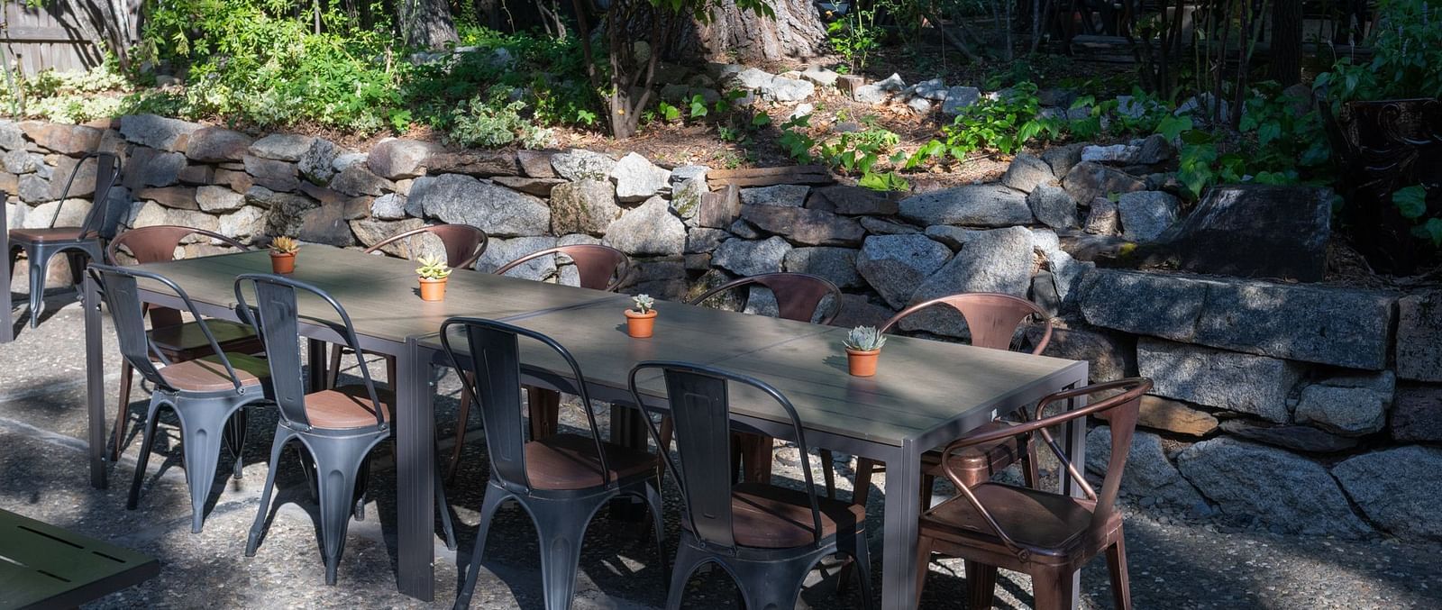Outdoor dining setup with long communal tables among greenery at The Groveland Hotel.