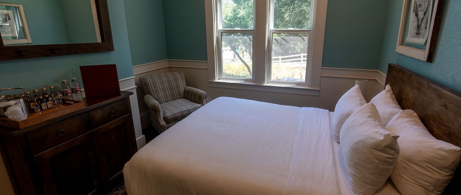 Guest room with a plush bed, wooden furnishings and bright windows at The Groveland Hotel.