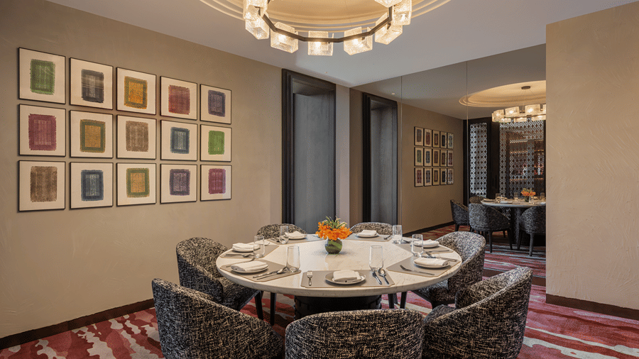 Club Lounge private dining area with a round marble table, textured armchairs, a glass-block chandelier and framed artworks at The Residency Signature Madurai.