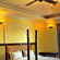 A room with a twin large bed, spreads, pillows, a fan, chairs, and a chandelier. | Hotel Devnadi, Haridwar