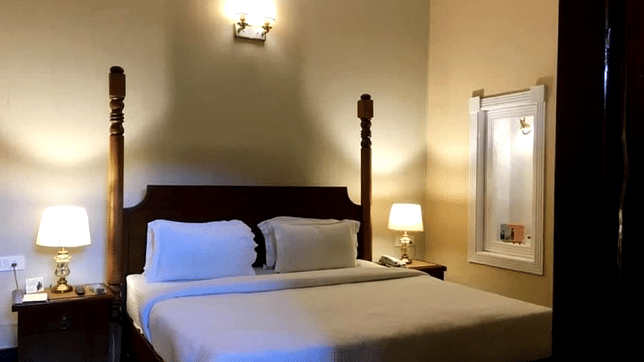 A room with a large bed, spreads, pillows, and lights. | Hotel Devnadi, Haridwar