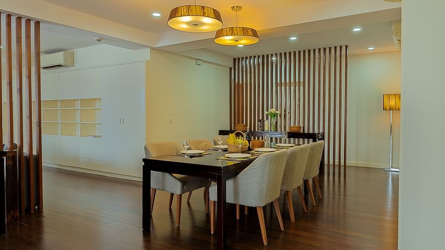 A dining area with a wooden table, chairs, and a chandelier overhead | Penthouse | Central Mansions, Phnom Penh
