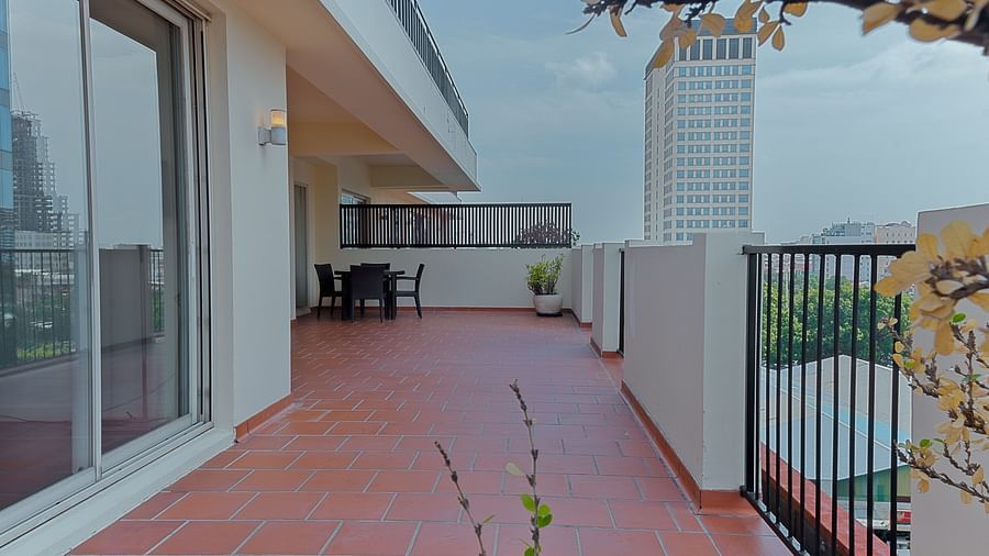 An outdoor patio area with a red tiled floor and a railing | Penthouse | Central Mansions, Phnom Penh