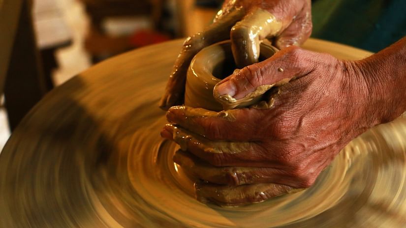 A close shot of a person using clay to make an item out of clay.