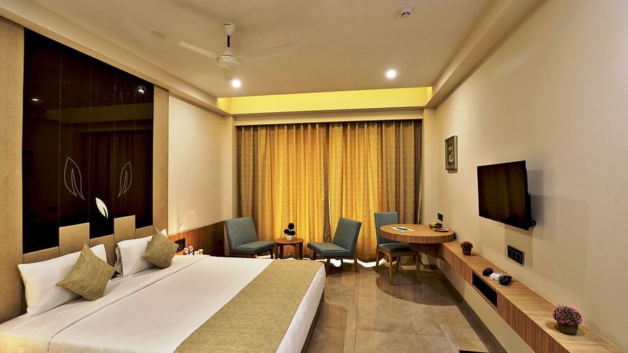 Double bed with gold pillows and bed runner with a wall mounted tv opposite it inside Executive Room - VITS Devbhumi, Dwarka