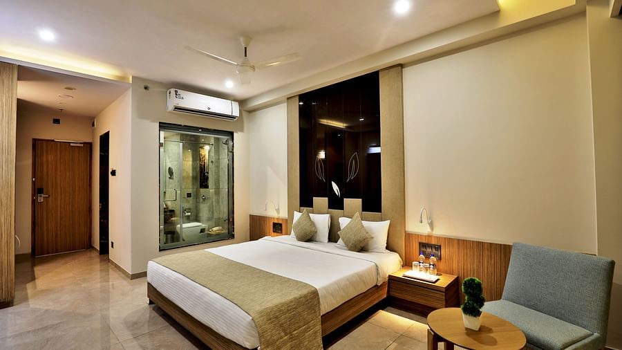 A double bed with gold pillows and bed runner next to side tables and lamps on it inside Executive Room - VITS Devbhumi, Dwarka