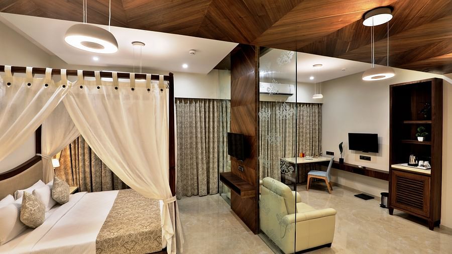 Overview of the Suite Room with a king bed, single seater sofas next to a marble wall - VITS Devbhumi, Dwarka