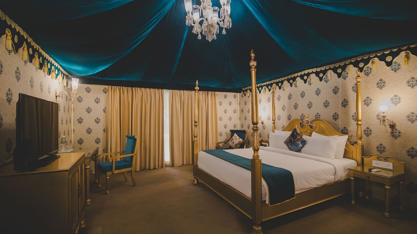 Image of Royal Luxury Tent with Balcony with a bed and a chandelier hanging from the ceiling at Rajasthali Resort and Spa.