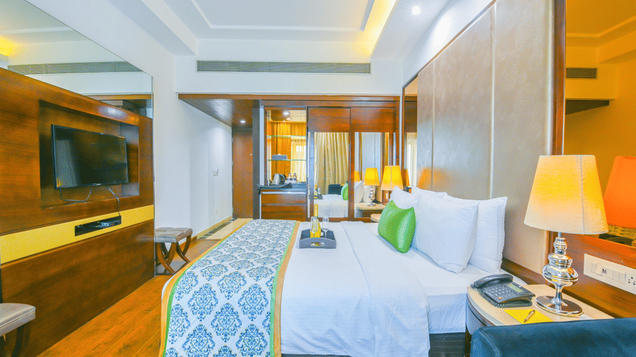 A well-appointed guest room with a large bed, turquoise patterned runner, wooden wall panels, and a flat-screen TV - Flute Boutique By Hotel 91, Jaipur